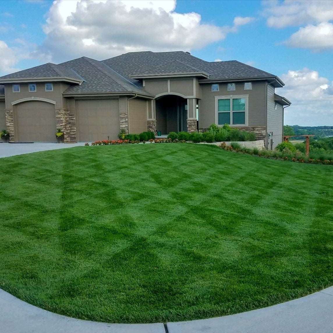 Beautifully manicured lawn with a crisscross pattern in front of a modern suburban home.