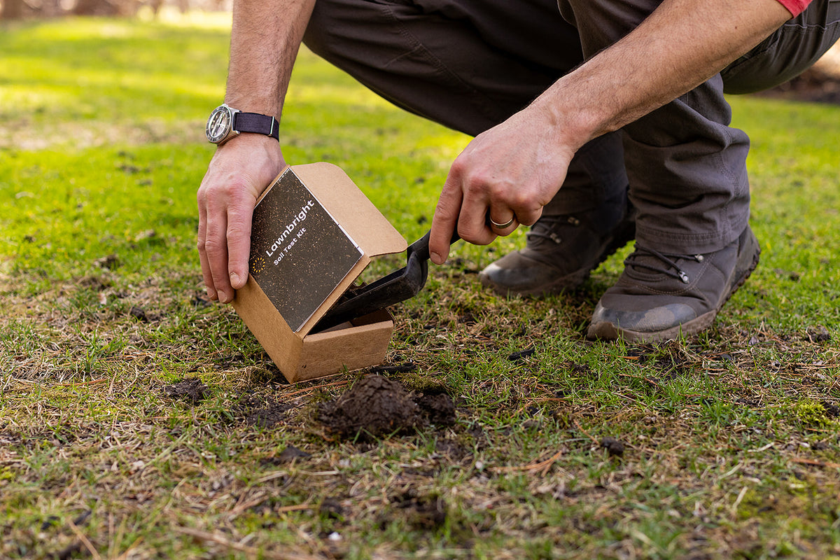 A man puts a scoop of dirt from his lawn into a box labeled Lawnbright Soil Test Kit.